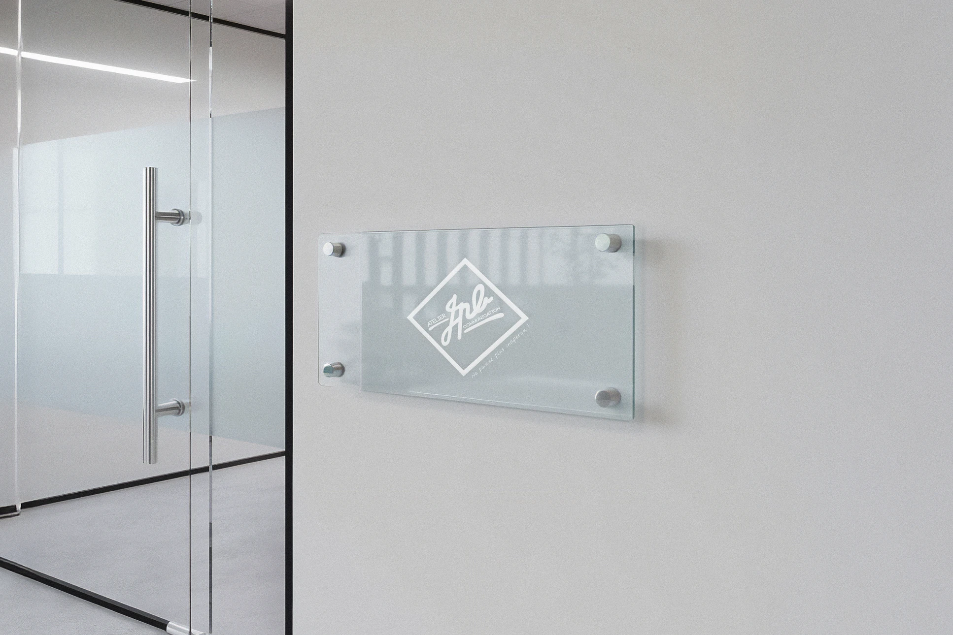 Photographie en gros plan d'une plaque professionnelle de haute qualité, gravée ou imprimée, affichant un nom d'entreprise et un logo professionnel, posée sur une surface moderne, avec un éclairage professionnel qui met en évidence la finition et la précision du travail. L'arrière-plan montre légèrement un atelier de production équipé de machines modernes, créant un contexte de fabrication artisanale de qualité.
