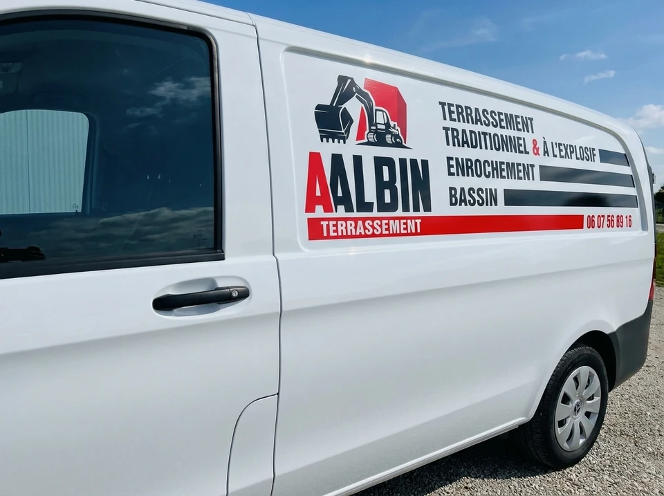 Technicien appliquant un film de protection transparent sur le pare-brise d'un véhicule noir dans un atelier automobile professionnel
